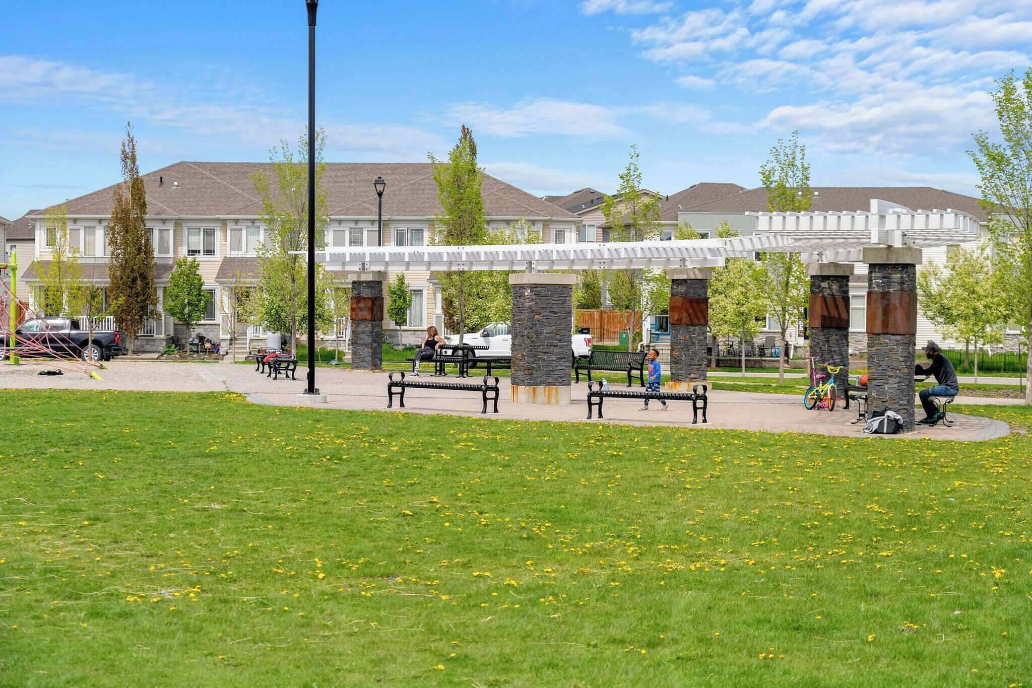Un parc doté de bancs et d’une aire de jeux, entouré d’immeubles d’habitation.