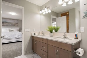 Un bagno moderno con uno specchio grande, due lavabi, una pianta in vaso e un portasciugamani.
