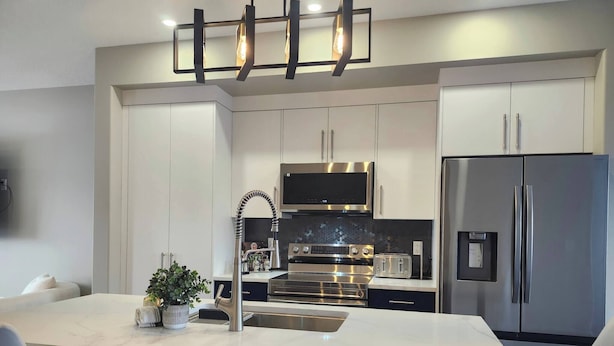 A modern kitchen with a central island, stainless steel appliances, and a minimalist design.