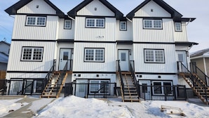 A multi-story residential building with a symmetrical facade, featuring a central entrance with a door and a staircase leading to the upper floors.
