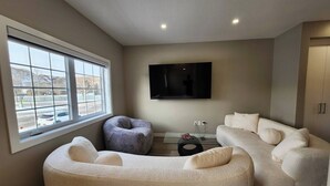 A modern living room with a large window, a flat-screen TV, and a sofa.