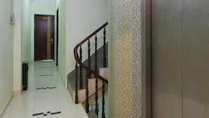 Un pasillo con una escalera, una puerta al final y un muro con textura.