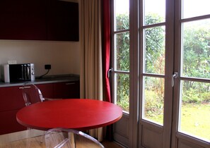 A room with a red table, a microwave, and a window with a view of greenery. - Joia Luxury Hotel Luxury Apartments (Brusaporto)