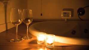 A wooden table with two wine glasses and two lit candles. - Joia Luxury Hotel Luxury Apartments (Brusaporto)