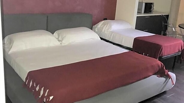 A hotel room with two beds, a kitchenette, and a small seating area. - Joia Luxury Hotel Luxury Apartments (Brusaporto)