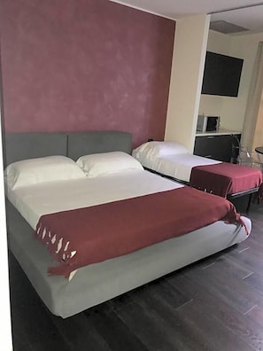 A hotel room with two beds, a kitchenette, and a small seating area. - Joia Luxury Hotel Luxury Apartments (Brusaporto)