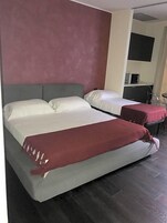 Una camera d'albergo con due letti, angolo cottura e piccola zona salotto.