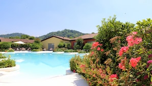 A swimming pool surrounded by lush greenery and a hillside. - Joia Luxury Hotel Luxury Apartments (Brusaporto)