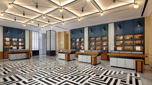 A hotel lobby with a geometric patterned floor, multiple reception desks, and wall-mounted display shelves. - Four Points by Sheraton Tianshui (Tianshui)
