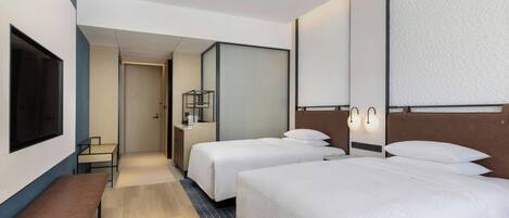 Een hotelkamer met twee bedden, een bankje, een bureau en een televisie.