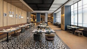 A modern restaurant with long communal tables, individual booths, and a patterned floor. - Four Points by Sheraton Tianshui (Tianshui)