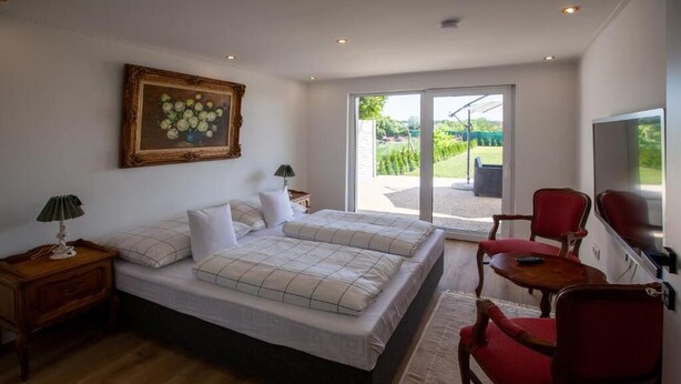 Een slaapkamer met een tweepersoonsbed, een televisie en een balkon met uitzicht op de tuin.