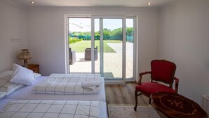 Een slaapkamer met twee bedden, een rode stoel en een houten tafel.
