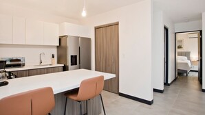 A modern kitchen with a central island, bar stools, a built-in oven, and a refrigerator.