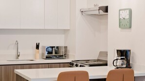 A modern kitchen with white cabinets, a built-in stove, and two bar stools.