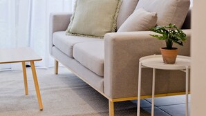 A living room with a sofa, a small table, and a potted plant.