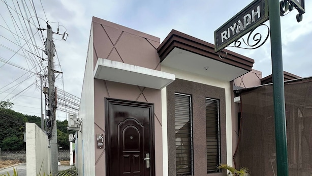 A small, modern building with a dark brown door and windows, labeled "RIYADH" and "SEOUL". - Cozy 1-Bedroom House Rental in Hermosa, Philippines (Hermosa)