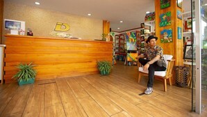 A reception area with a wooden reception desk, a TV, and a sign that reads "Downtown." There are potted plants and artwork on the walls. - La Fortuna Downtown Boutique Hotel (La Fortuna)