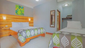 A hotel room with two beds, wooden headboard, a mirror, and a wall-mounted artwork. - La Fortuna Downtown Boutique Hotel (La Fortuna)
