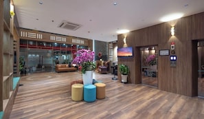 Un hall d’entrée moderne avec un plancher en bois, un espace salon et une grande plante en pot.