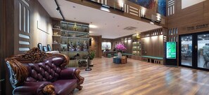 Un intérieur moderne avec un canapé en cuir, des étagères en bois ornées d’objets décoratifs, et, au fond, un restaurant appelé « The Cosy ».