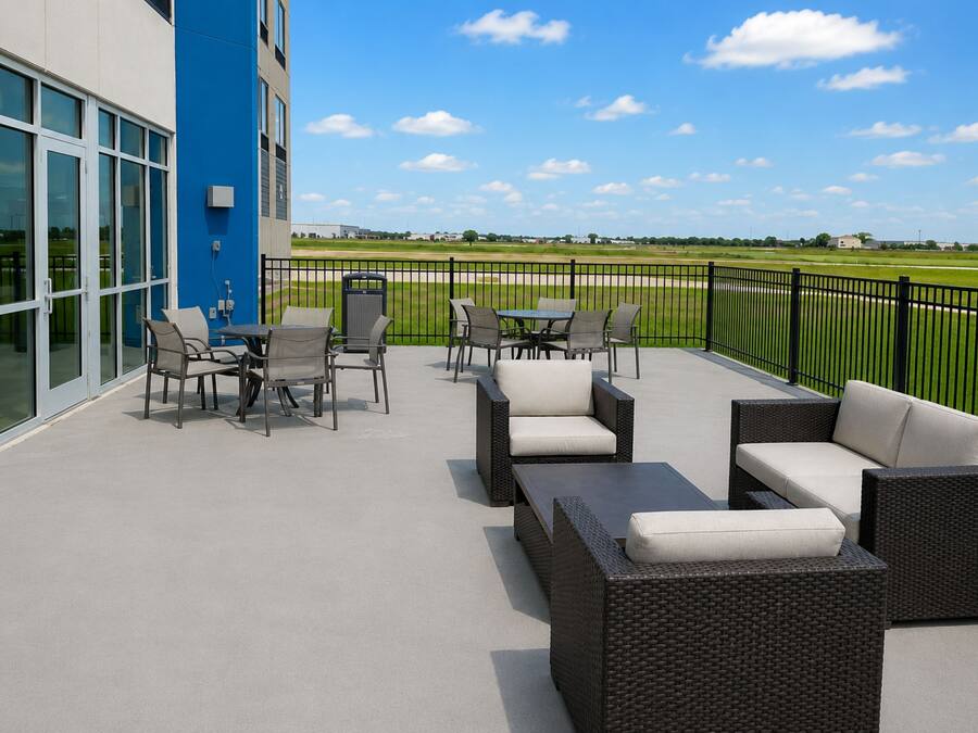 An outdoor patio with wicker furniture and a view of a green field.