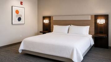 Habitación de hotel con una cama grande, dos mesitas de noche, un cabecero y una lámpara fijada a la pared.