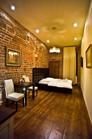 A room with a brick wall, a bed, a table with chairs, and a hanging light fixture. - Apartamenty Torun Rynek Staromiejski (Torun)