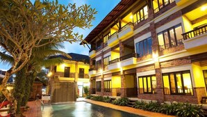 A multi-story hotel with a swimming pool, balconies, and a tropical garden. - Tony Lodge (Takua Pa)