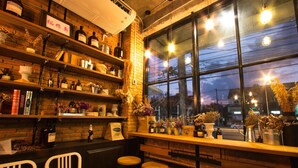 A bar area with shelves of bottles, a brick wall, and a large window with a view of the street. - Tony Lodge (Takua Pa)