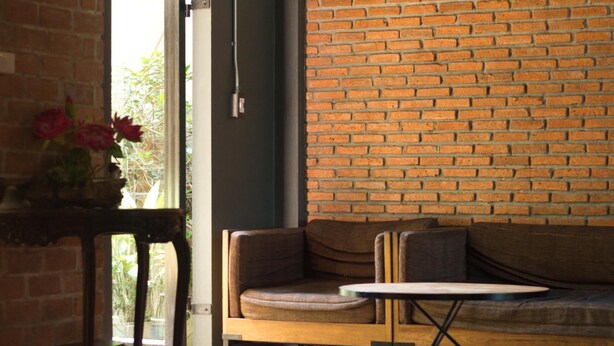 A room with a brick wall, a wooden bench, and a small table. - Tony Lodge (Takua Pa)
