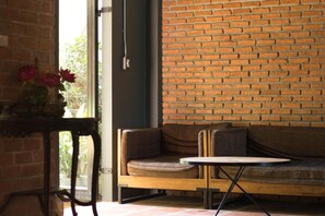 A room with a brick wall, a wooden bench, and a small table. - Tony Lodge (Takua Pa)