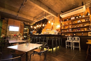 Ein Restaurant Innenraum mit freiliegenden Backsteinwänden, hängenden Lampen und einer Bar mit Regalen voller Flaschen.