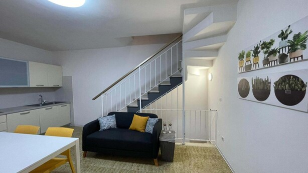 Ein kompakter Wohnraum mit Küche, Essbereich und einer Treppe.