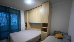 Ein Schlafzimmer mit zwei Betten, einem Kleiderschrank und einem Fenster mit Vorhängen.