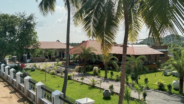 A resort with multiple buildings, a well-maintained lawn, and palm trees. - PRABANCH GARDENS - A CONSCIOUS STAY (Chengalpattu)