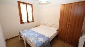 A bedroom with a bed, a wooden wardrobe, a window with curtains, and a ceiling light fixture. - Apartment Retreat near the Adriatic Sea (Rosolina Mare RO)