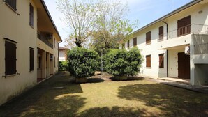 A courtyard with a pathway, surrounded by buildings with balconies and windows. - Apartment Retreat near the Adriatic Sea (Rosolina Mare RO)