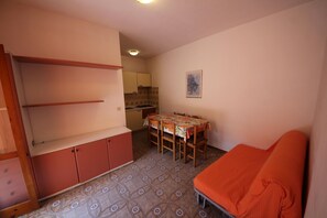 A compact room with a dining table, a sofa, and a kitchenette. - Apartment Retreat near the Adriatic Sea (Rosolina Mare RO)