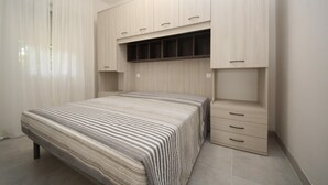 A bedroom with a bed, a wardrobe, and a built-in shelf. - Stylish Stay for 4 near Porto Caleri (Rosolina Mare RO)