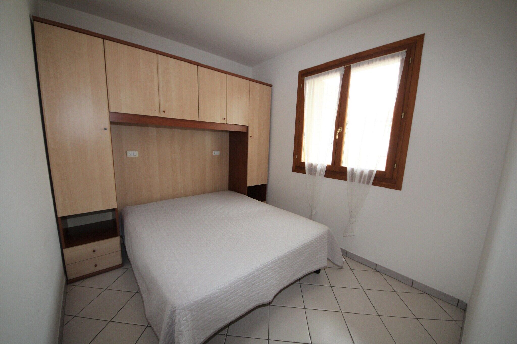 Een slaapkamer met een bed, een houten garderobe en een raam met gordijnen.