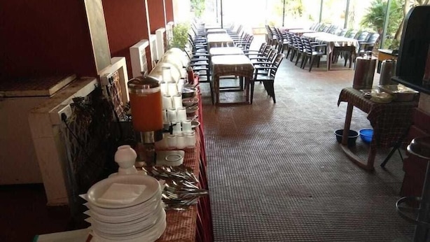 A restaurant with a long counter, tables, and chairs. - Ginger Tree Boutique Resort (Anjuna)