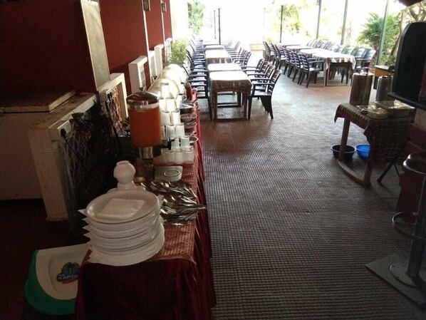 Un ristorante con un lungo bancone, tavoli e sedie.