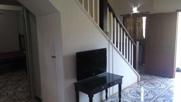 Una escalera con un televisor sobre una mesita al pie.