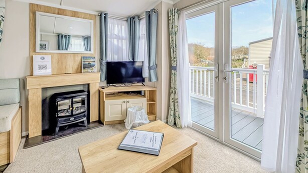 Ein Wohnzimmer mit Kamin, Fernseher und Blick ins Freie.
