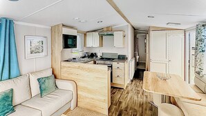 Ein kompaktes Wohnmobil-Interieur mit einer Küchenzeile, einem Essbereich und einer Sitzecke.