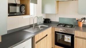 Eine moderne Küche mit Spüle aus Edelstahl, einem Gasherd und Holzschränken.