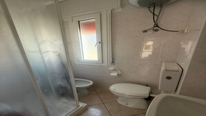 A small bathroom with a toilet, bidet, and a window. - Beachside Villa For a Family (Rosolina Mare RO)