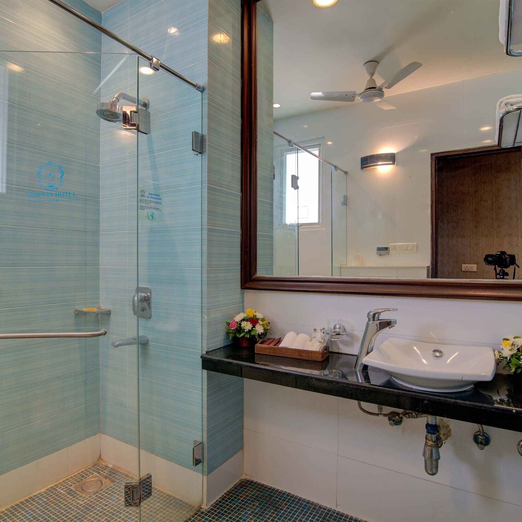 A modern bathroom with a glass shower enclosure, a vanity with a sink, and a mirror above it.