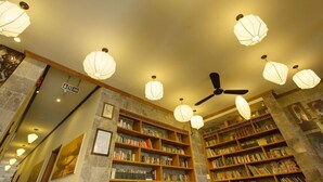 A library with ceiling fans, bookshelves, and a sign indicating an exit. - Vinh Hung Library Hotel (Hoi An)